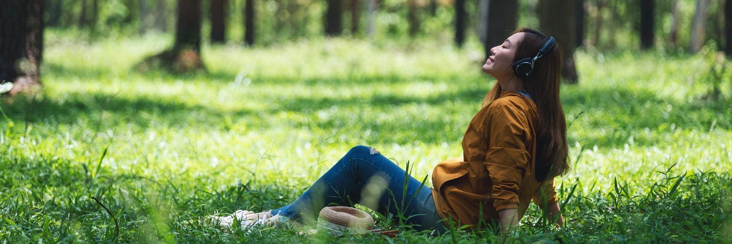 A woman resting on the grass in a sunlit wood