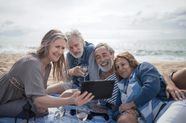 Four older friends at the beach taking a selfie together, smiling