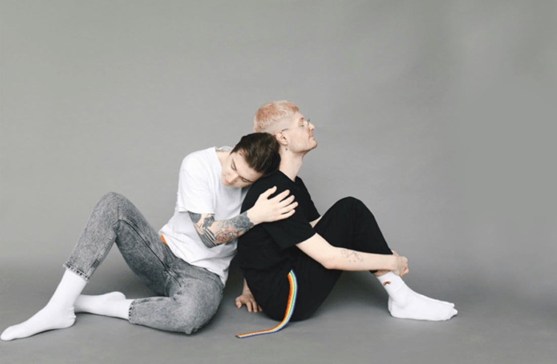 Two young people sitting close together, leaning on each other