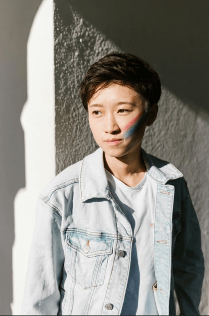 A young person with rainbow face paint on one cheek at a pride event