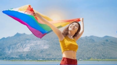 A person holding a rainbow flag open above their head
