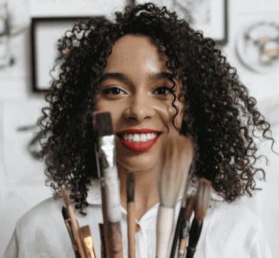 A woman with curly hair smiling behind a row of paint pots