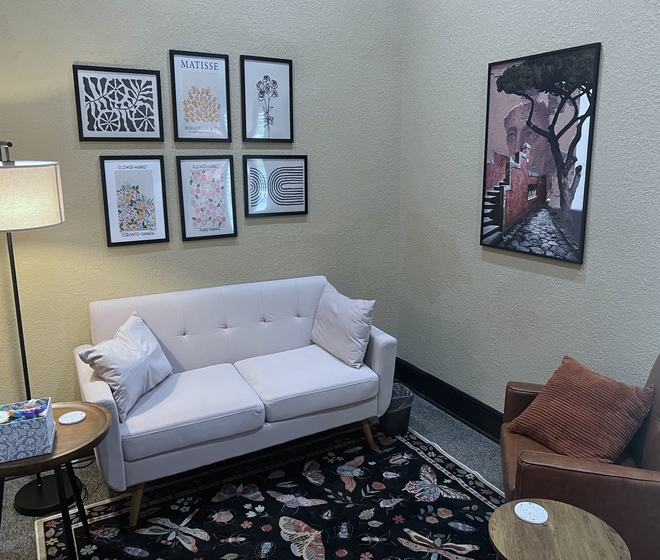 A therapy room with a gallery wall and a soft armchair