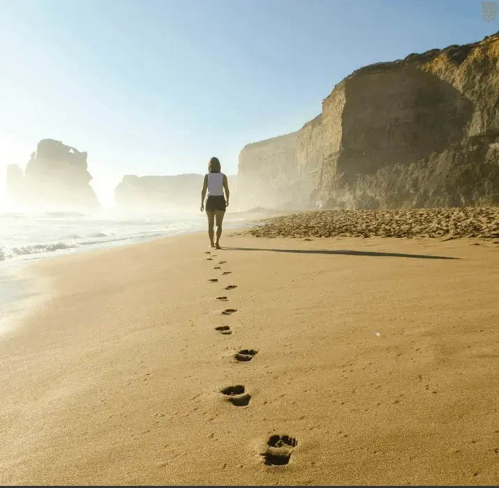 Two people walking a shoreline path in low sunlight